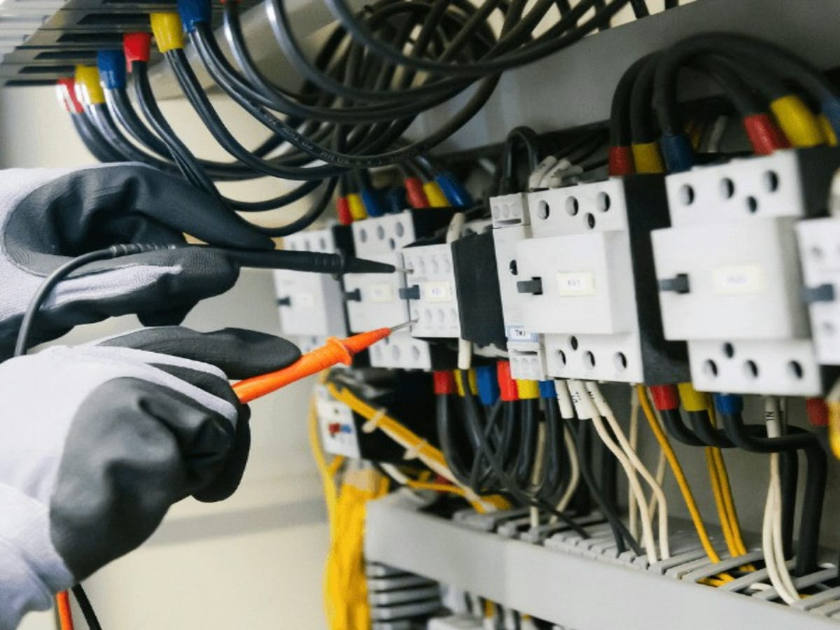 Electrician testing a home electrical panel with a multimeter