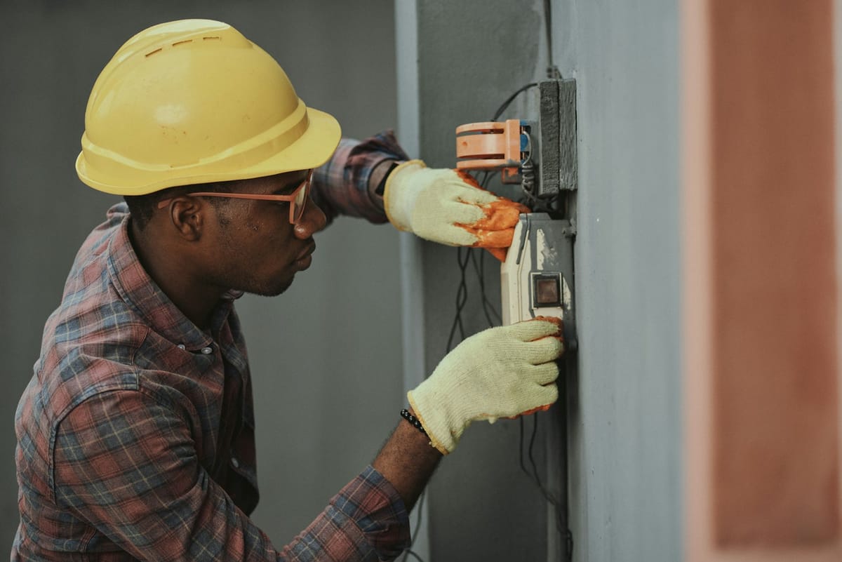 Professional electrician in safety gear wiring an electrical box